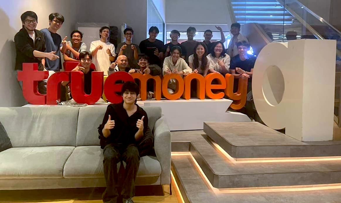 The team posing around the office sign